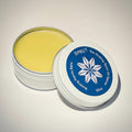 Close up photo of Sprüt Nursing Hands Balm with lid removed showing bright yellow colour and brand logo with text 