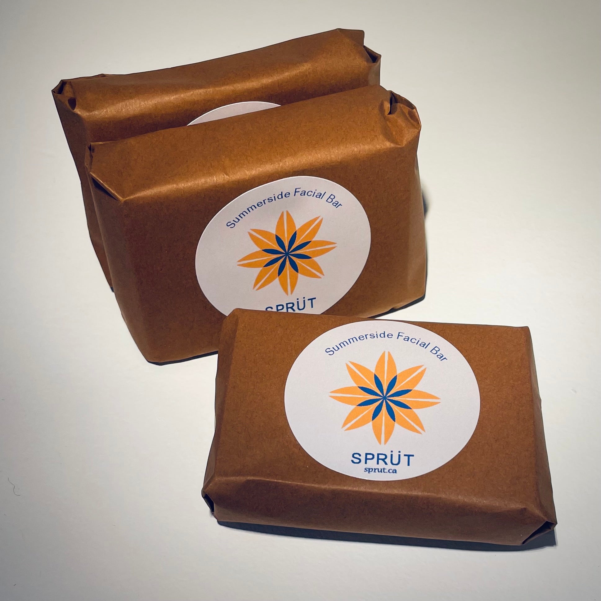 Three brown wrapped soap products with 'Sprüt’ logo on a light background
