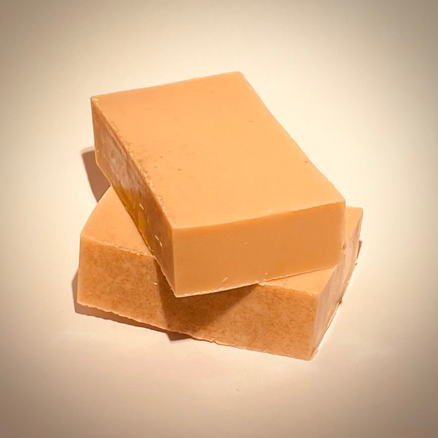 Two bars of amber coloured soap stacked on a neutral background